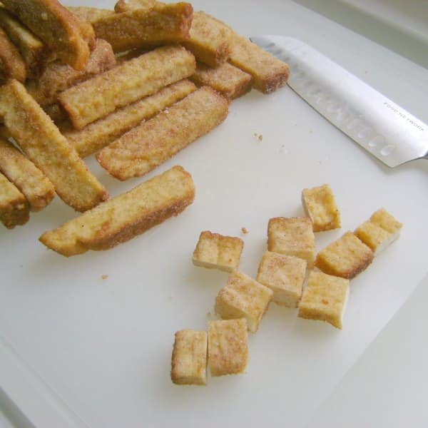 Cubed frozen french toast sticks on a cutting board.