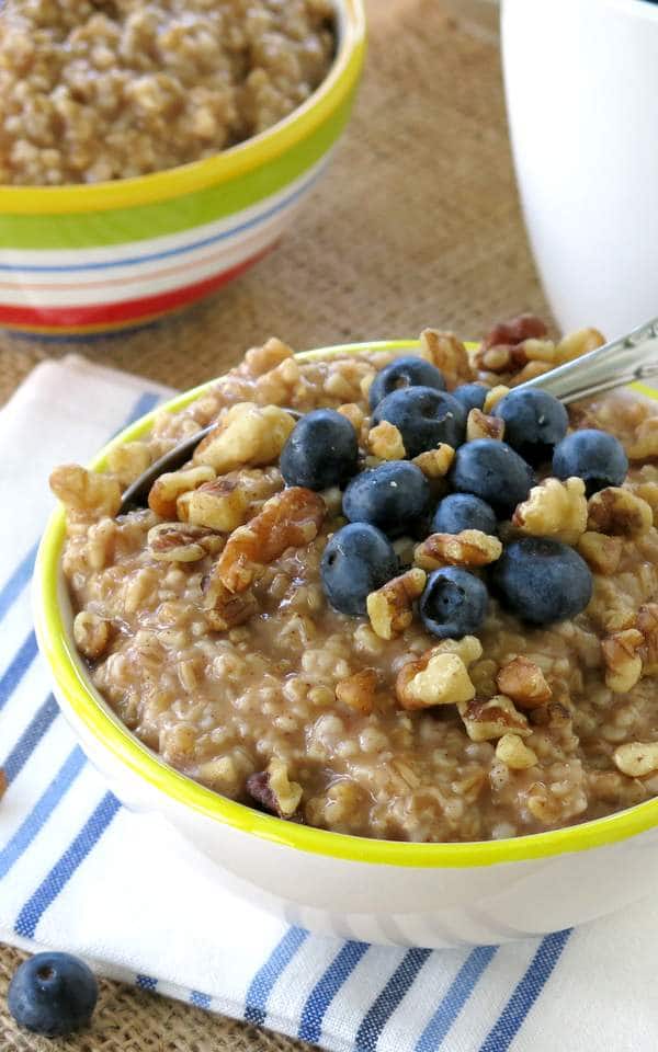 Bowl of steel cut oatmeal cooked in a Crock Pot topped with blueberries and walnuts.