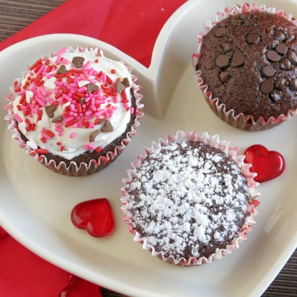 three chocolate vegan cupcakes with different toppings