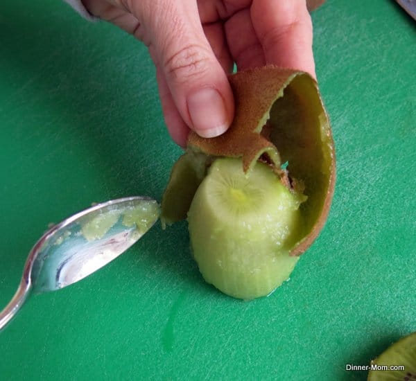 Kiwi fruit being peels on a cutting board