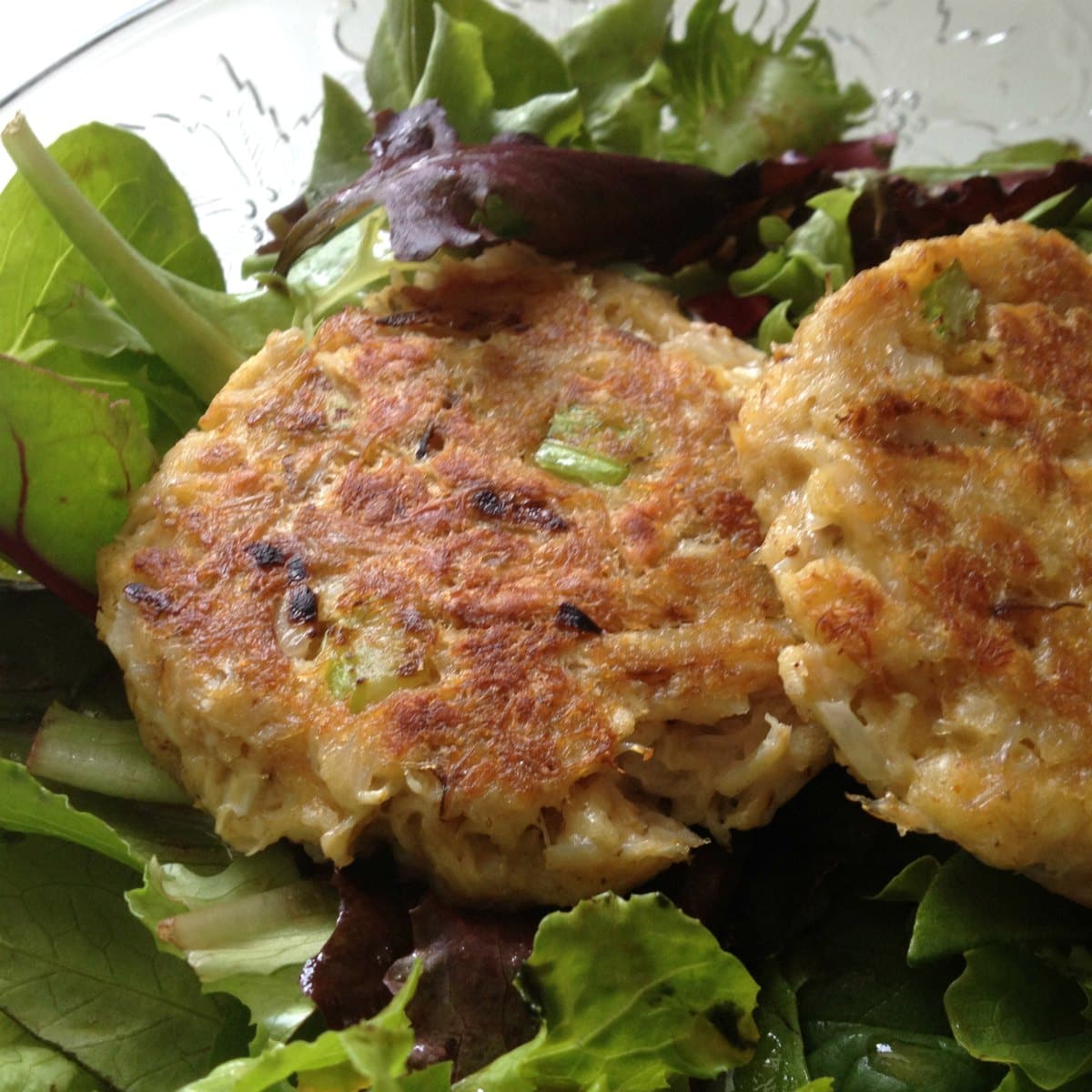 Two crab cakes on salad greens