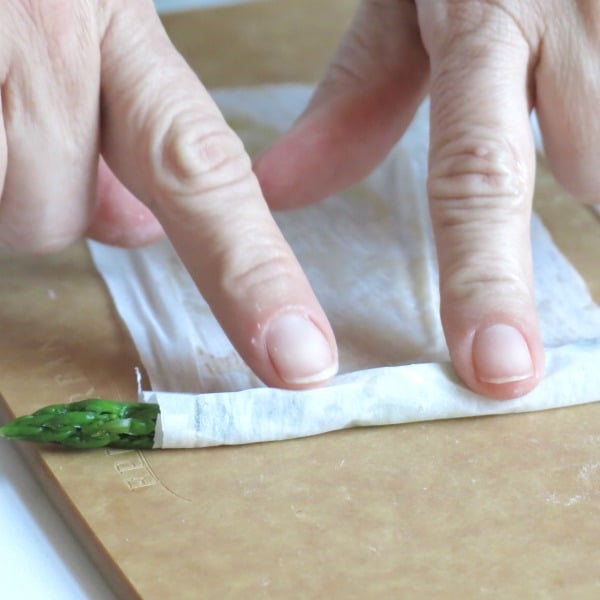 Asparagus being rolled in phyllo dough.