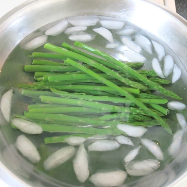 Blanched asparagus in bowl with ice.