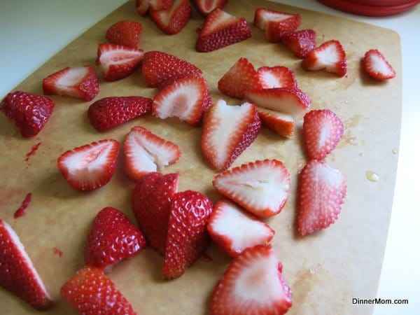Sliced strawberries on a cutting board.