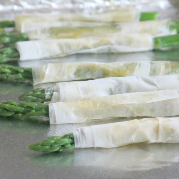 Asparagus wrapped in phyllo dough on a baking sheet.