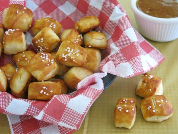 Homemade pretzel bites in basket with raspberry honey mustard sauce with 3 bites outside of the basket