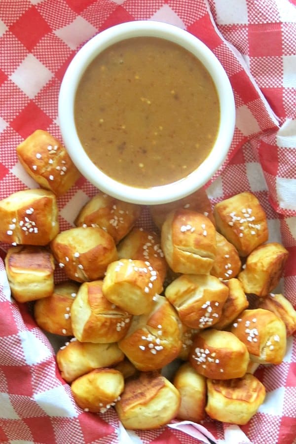 Soft pretzel bites in basket with cup of spicy raspberry mustard sauce.