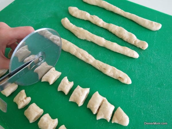 Pizza cutter cutting pretzel dough into bite sized pieces