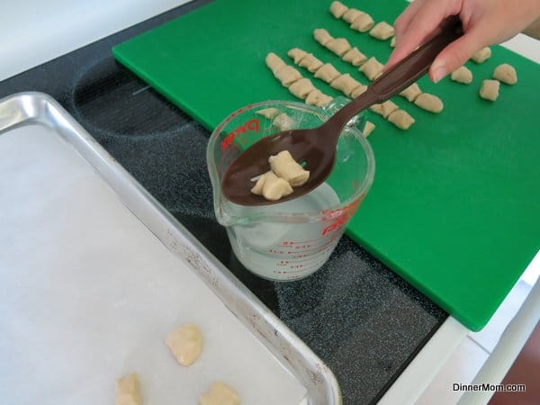 Homemade Pretzel Bites being dipped into baking soda and water mixture with a slotted spoon