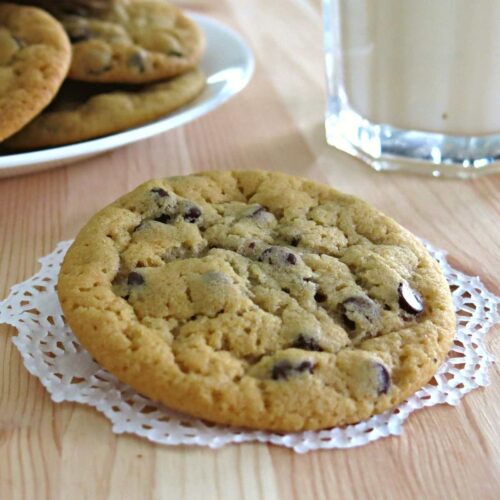 Plate with eggless chocolate chip cookies with plate of cookies and milk behind it.