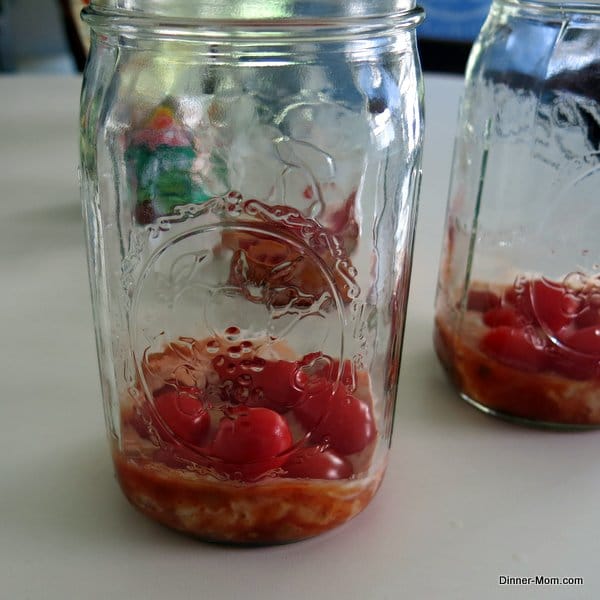 Dressing and grape tomatoes in bottom of mason jar.