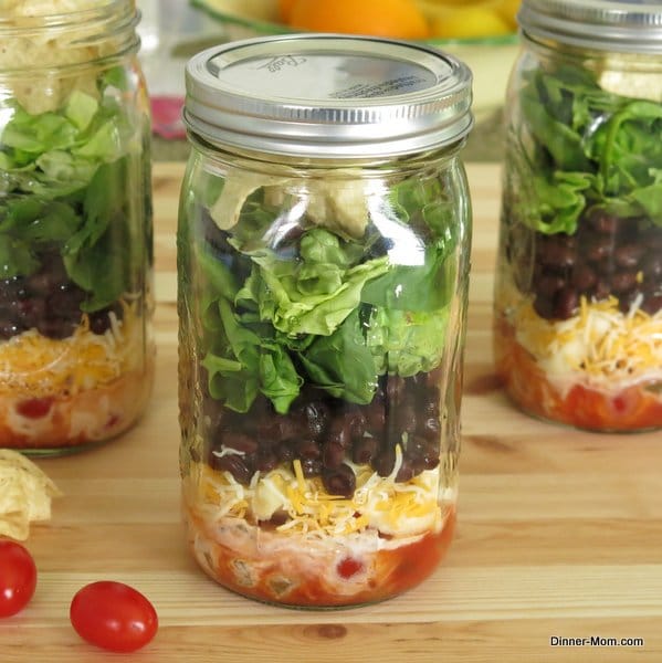 Layered Taco Salad in a mason jar plus with 2 more behind it.