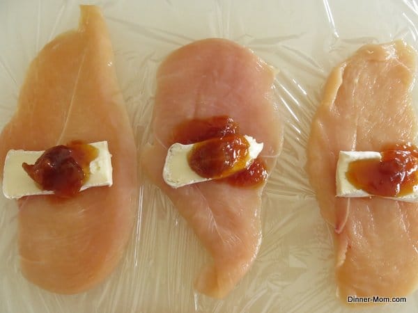 Raw chicken cutlets with mango chutney and brie in the center.