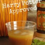 Pumpkin juice in glass with pumpkin and bottle from Wizarding World of Harry Potter.