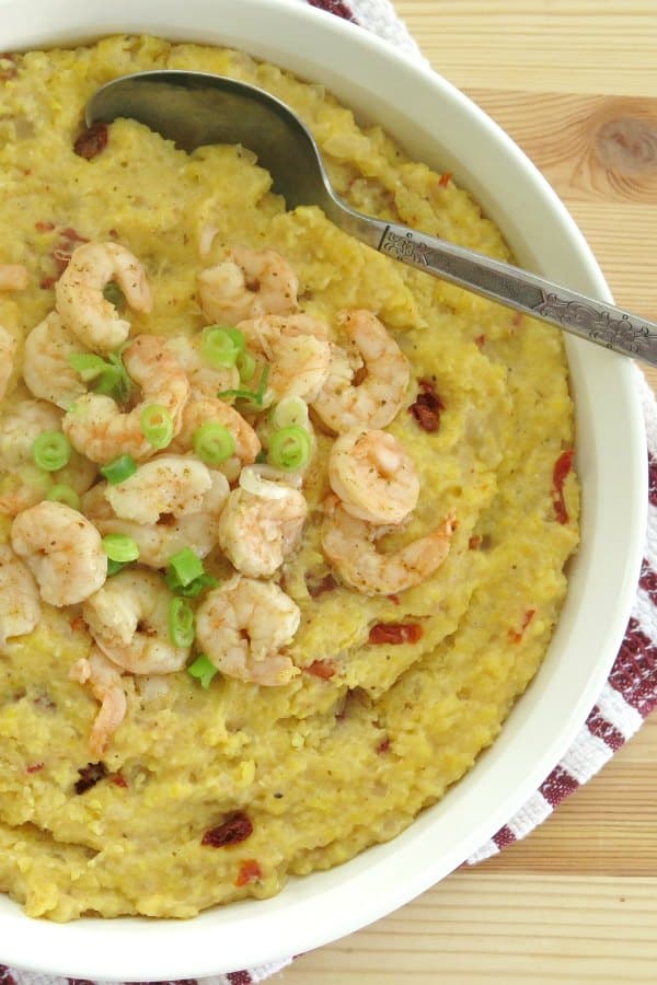 Large serving bowl with cajun shrimp and girts topped with sliced green onion