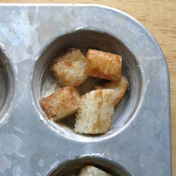 Several bread cubes in the well of a cupcake pan.