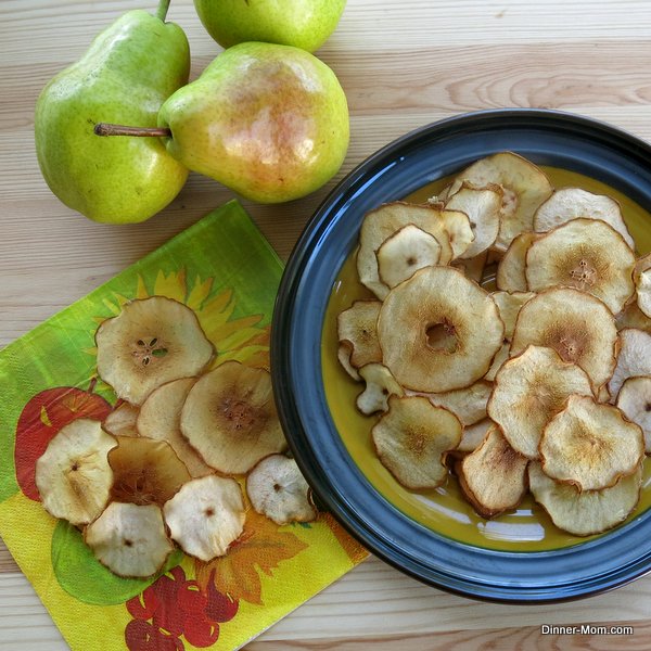 Les chips de poire sur une assiette à côté de poires entières