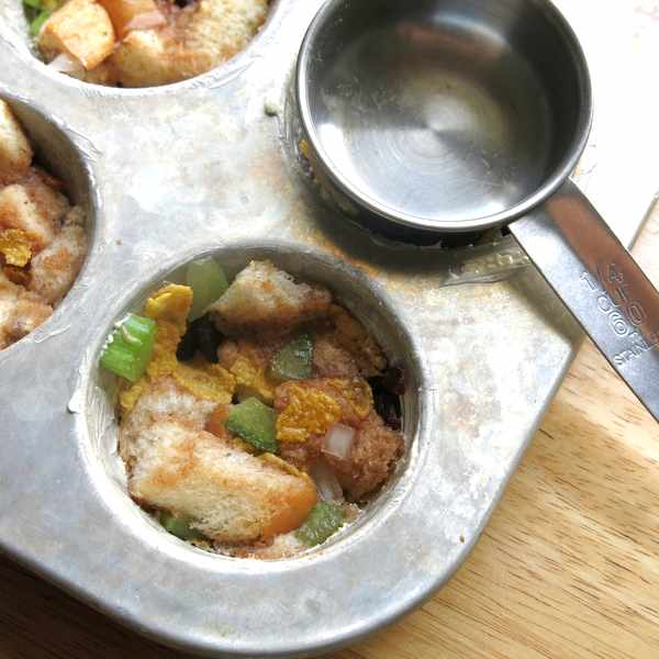 Stuffing Muffins in muffin tin pressed down with measuring cup.