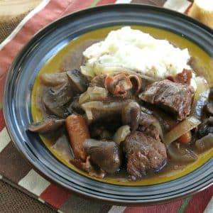 Crock pot beef bourguignon on plate with mashed potatoes