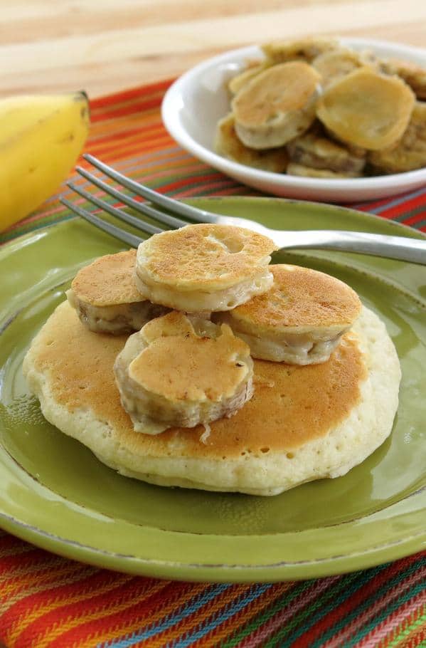 Large pancake topped with battered banana medallions and a fork.