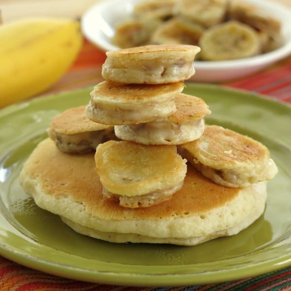 Battered bananas stacked on top of each other on a green plate.