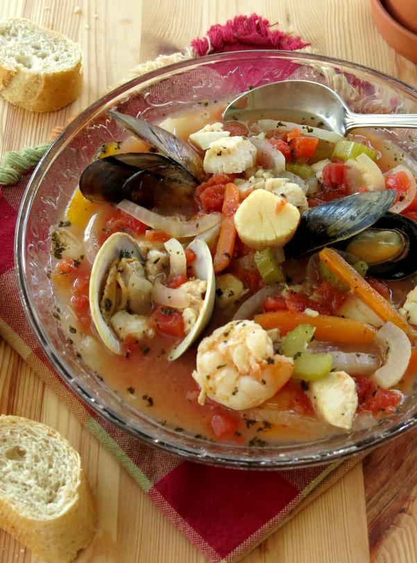 Easy Italian Seafood Stew in bowl with spoon and bread on the side