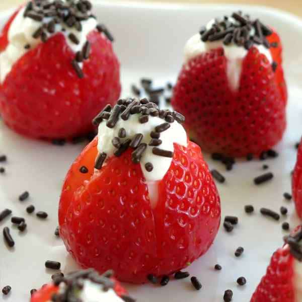 3 No-bake cheesecake stuffed strawberries on a plate topped with sprinkles