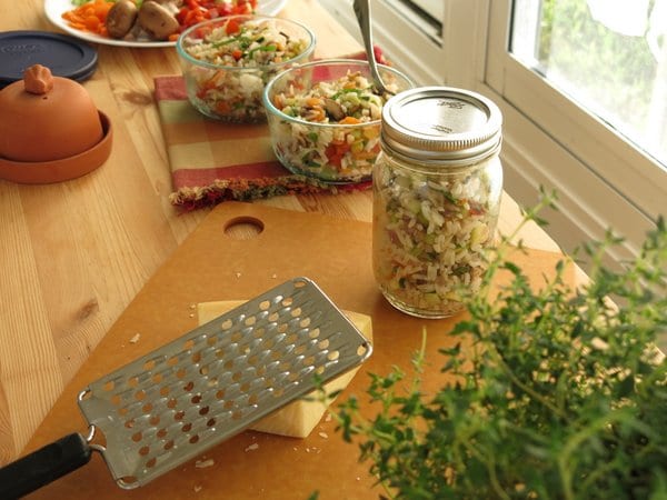 Work table with vegetable rice pilaf portioned into containers.