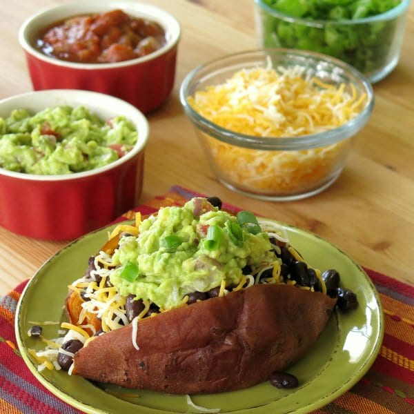 Loaded Crock-Pot Sweet Potatoes surrounded by little bowls with toppings