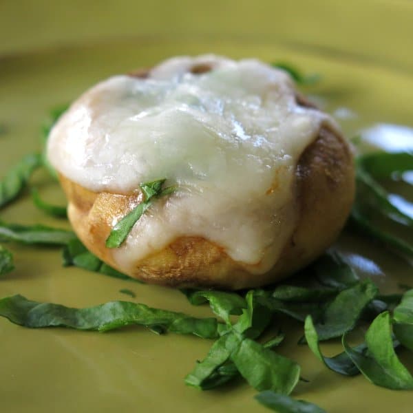 Mushroom Pizza Bite with Spinach and Mozzarella on top of spinach on a plate