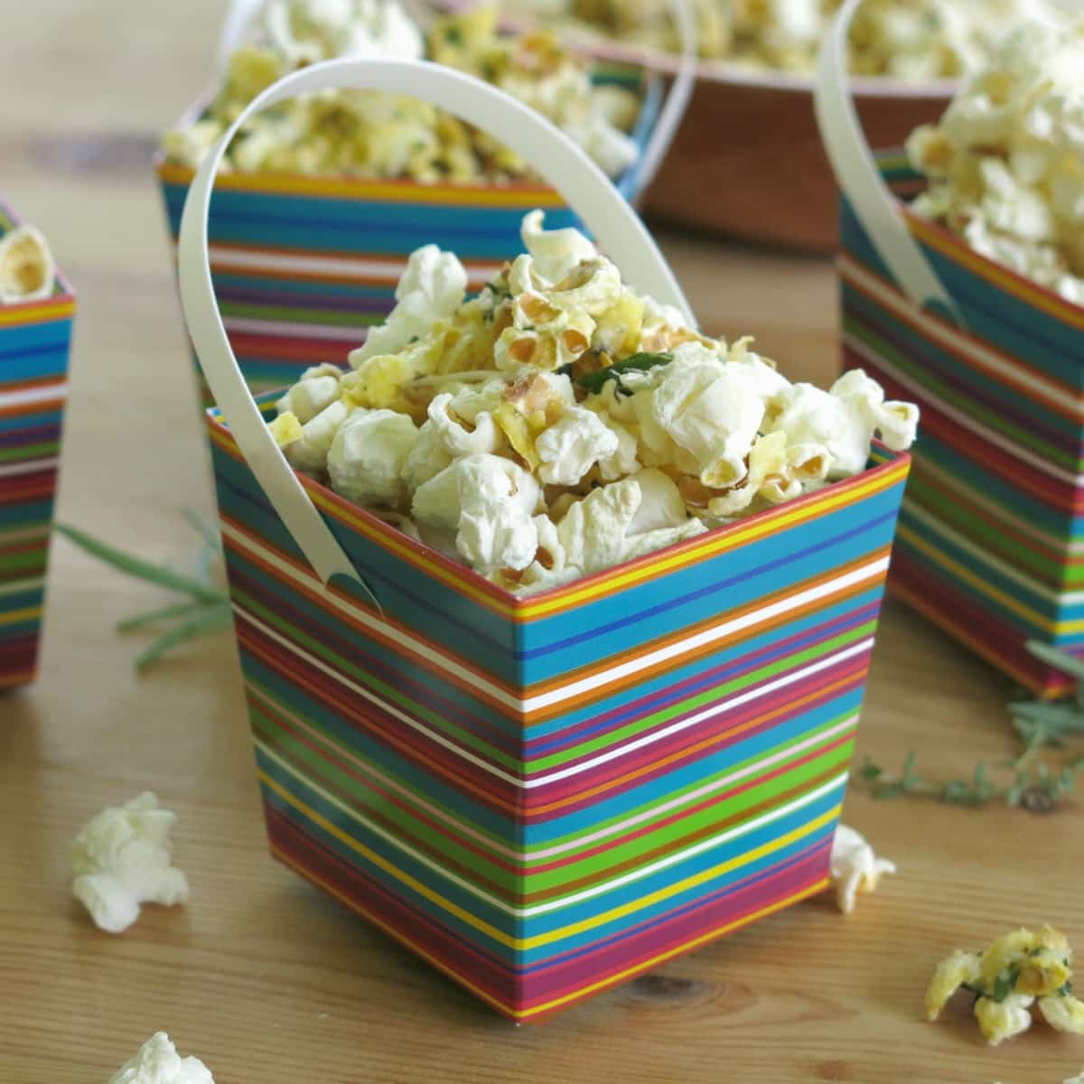 Savory popcorn topped with Parmesan cheese and fresh herbs in serving box.