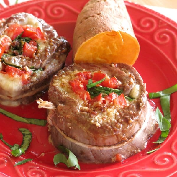 2 Spinach Stuffed Flank Steak Pinwheels on plate with a sweet potato.