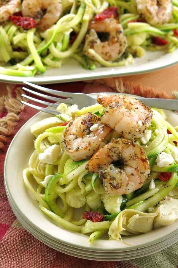 Shrimp Zoodles Recipe on a stack of plates with platter in the background