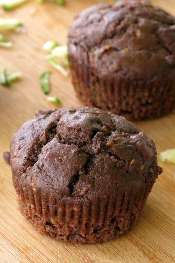 Two healthy Chocolate Zucchini Muffins on a cutting board.