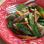 Sesame beef, snow peas and carrots on plate with fork