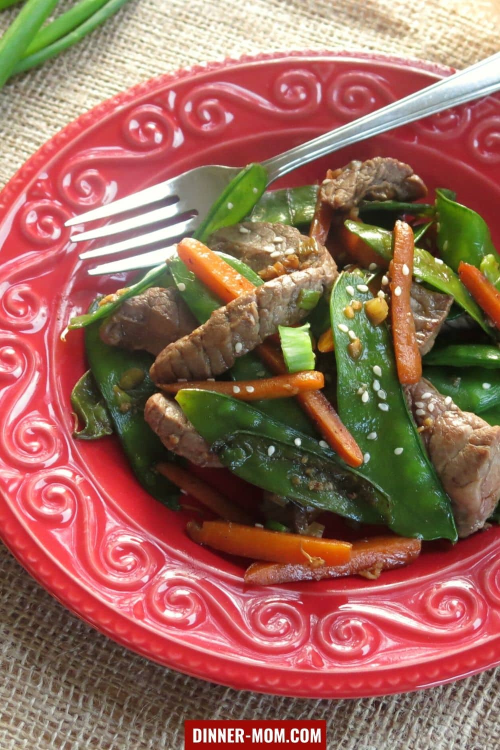 Sesame beef, snow peas and carrots on plate with fork