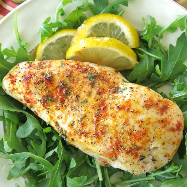 Baked Lemon Pepper Chicken breast on a bed of greens with lemon slices