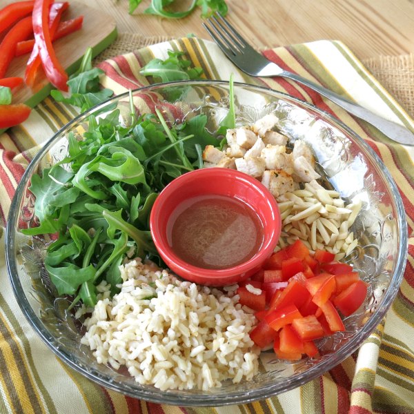 Ingredients for Chicken Arugula Rice Salad on plate separated into sections