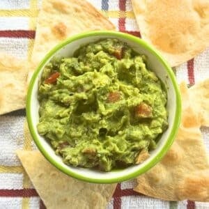 Bowl of one avocado guacamole surrounded by tortilla chips.