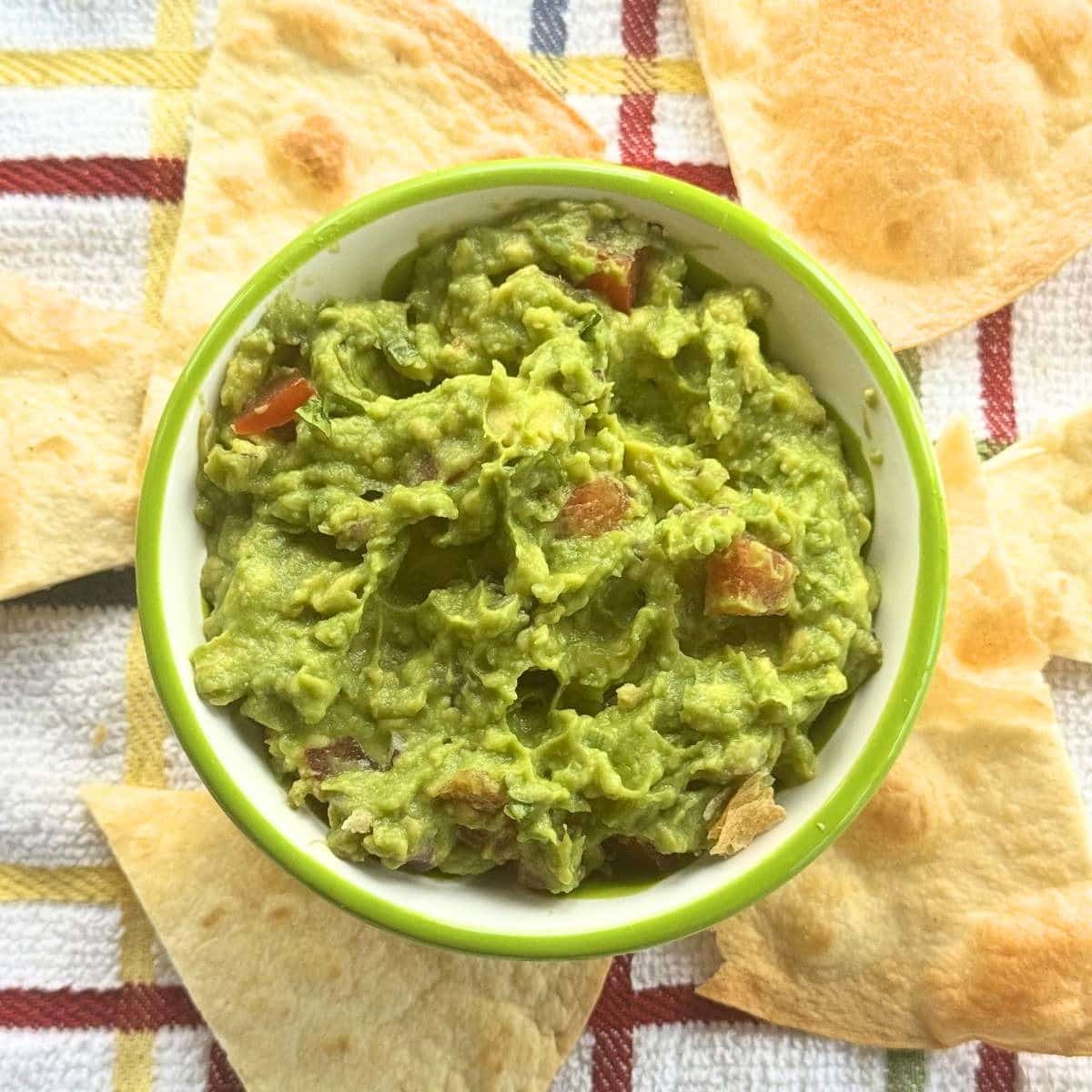 Bowl of one avocado guacamole surrounded by tortilla chips.