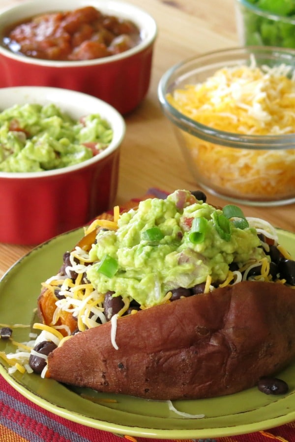 Loaded Sweet Potato surrounded by toppings in bowls on potato bar