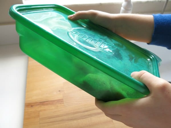 Chicken pieces inside a green oblong container with breading.