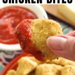 Fingers holding a garlic parmesan chicken bite that has been dipped in marinara sauce over a plate with more.