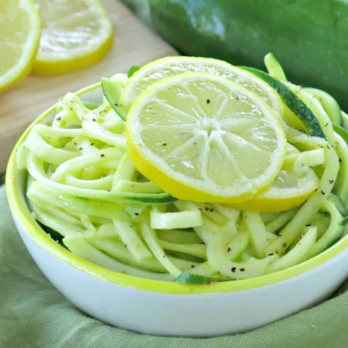 Lemon garlic zucchini noodles in a bowl with lemon slices on top