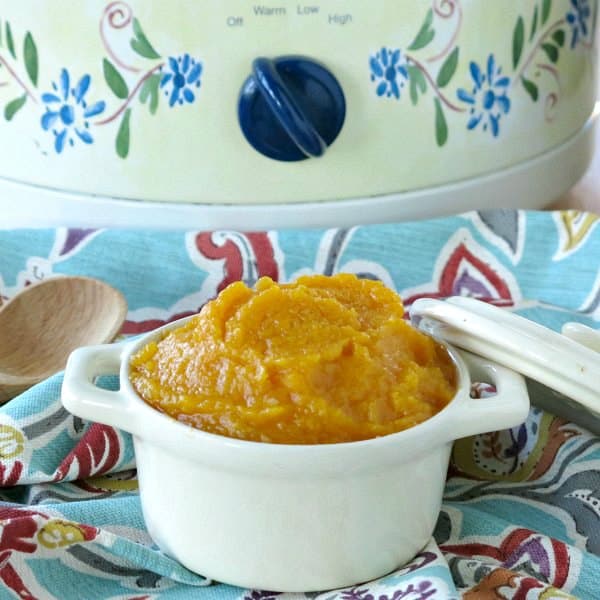 Crock-pot butternut squash in a bowl in front of a slow cooker