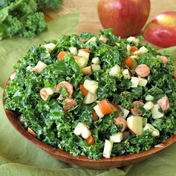 Kale apple slaw in bowl with apples in the background