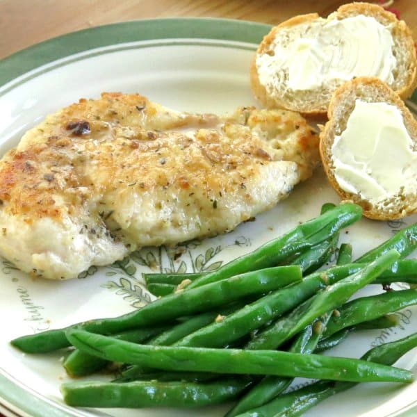 Pan Fried Lemon Chicken Cutlets drizzled with lemon sauce on plate with green beans