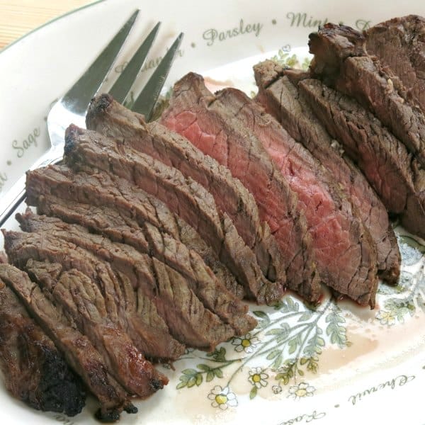 Slices of london broil on serving platter with fork.