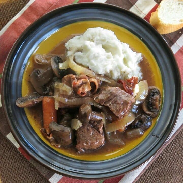 Plate with a serving of crockpot beef bourguignon with mashed potatoes.