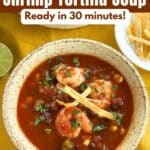 Shrimp tortilla soup with black beans, corn, cilantro, and crispy tortilla strips in a tomato broth.